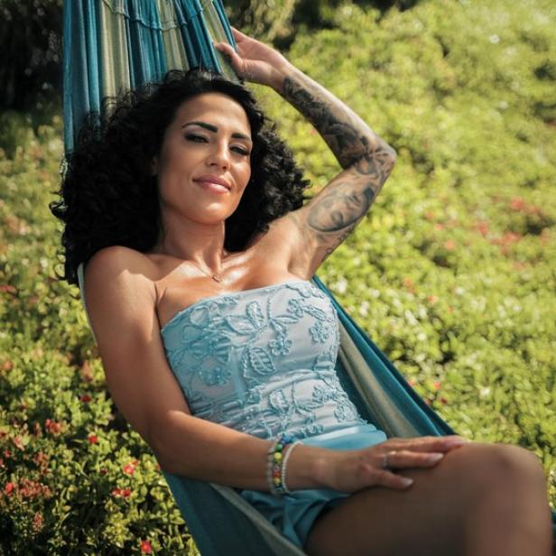 Elena Miras entspannt in einer Hängematte vor blühendem Grün.