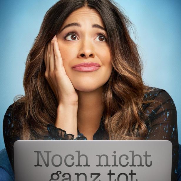 Eine Frau blickt mit Laptop, auf dem „Noch nicht ganz tot“ steht, nach oben.