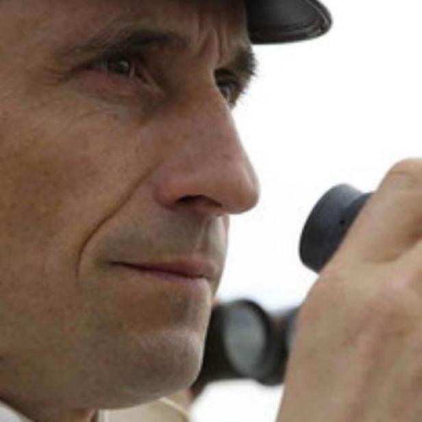 Ein Mann in Marineuniform blickt durch ein Fernglas.