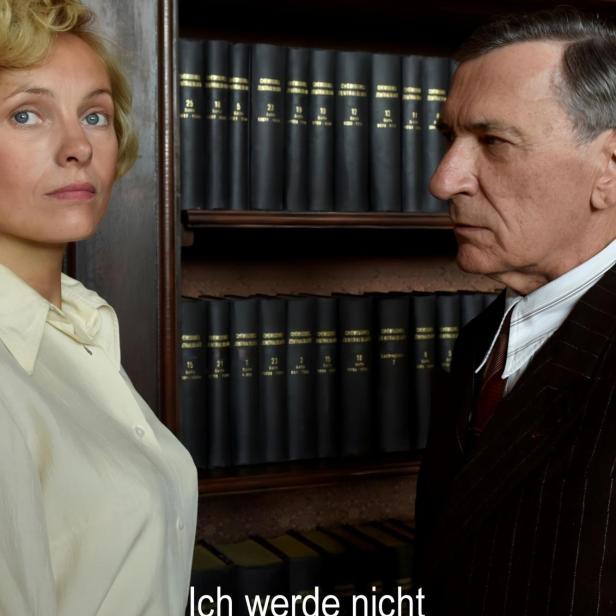 Eine Frau und ein Mann stehen vor einem Bücherregal; Filmposter „Ich werde nicht schweigen“.