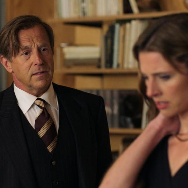 Ein Mann im Anzug schaut besorgt auf eine Frau mit dunklem Kleid.