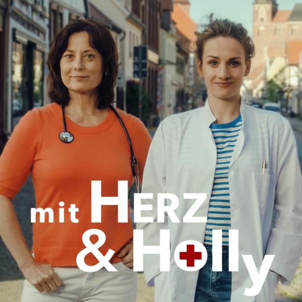 Zwei Ärztinnen stehen vor einer Stadtkulisse, im Vordergrund der Titel „mit Herz & Holly“.