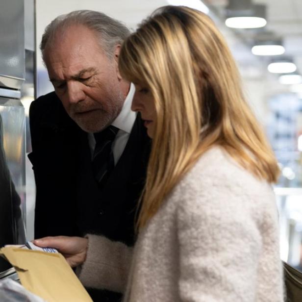 Mann und Frau beugen sich bei Bahnhofschließfach über Kuvert