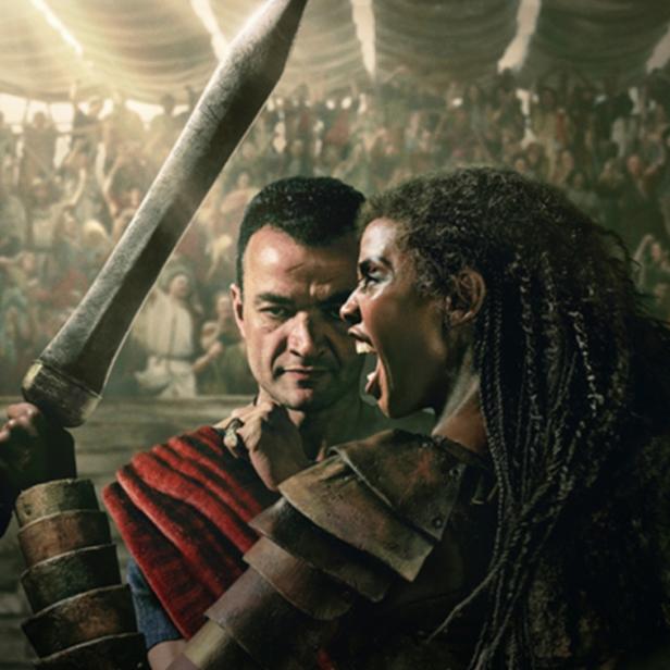 Schreiende Schwarze Gladiatorin hält in Arena Schwert in die Höhe