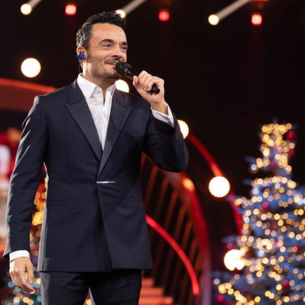 Giovanni Zarrella mit Mikro vor Christbaum im TV-Studio