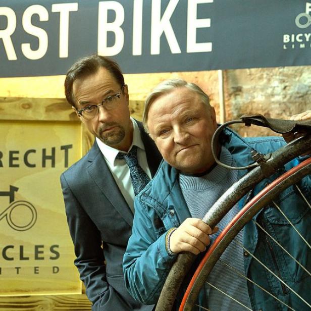 Jan Josef Liefers und Axel Prahl in ihren Tatort-Rollen  hinter einem alten Fahrrad auf einer Ausstellung