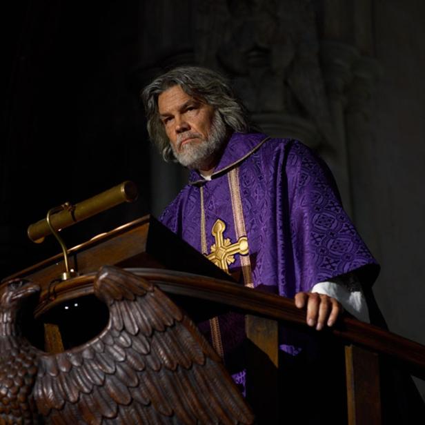 Ein alter bärtiger Priester steht auf der Kanzel im Ornat