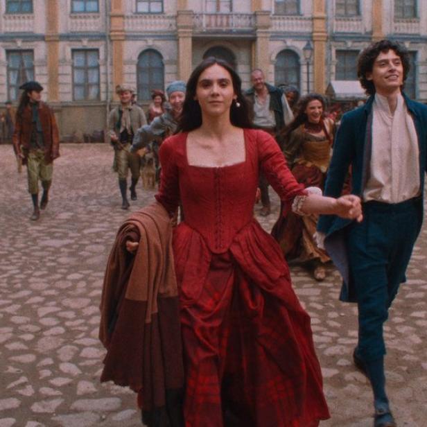 Havana Joy läuft als Maria Anna Mozart im roten Kleid über Kopfsteinpflaster