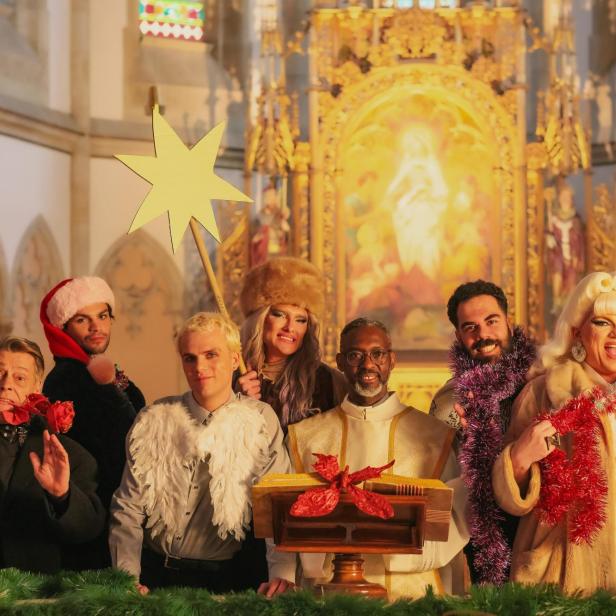 Schrille Gruppe in Weihnachts- und Engels-Aufmachung vor dem Altar einer Kirche, wo ein Schwarzer Priester am Pult steht