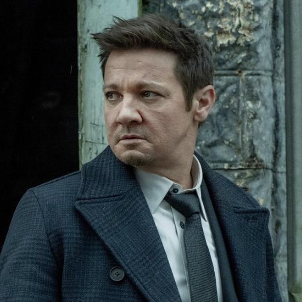 Jeremy Renner steht in seiner Serienrolle an einer Gebäudeecke