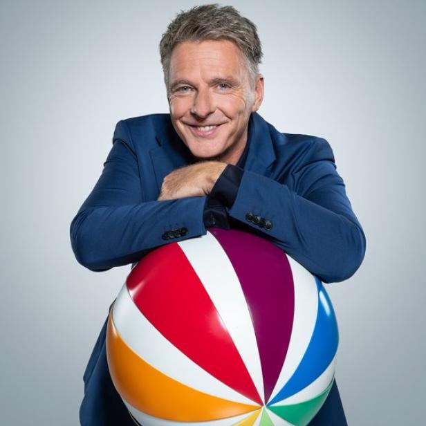 Jörg Pilawa stützt sich auf bunten Sat1-Logo-Ball