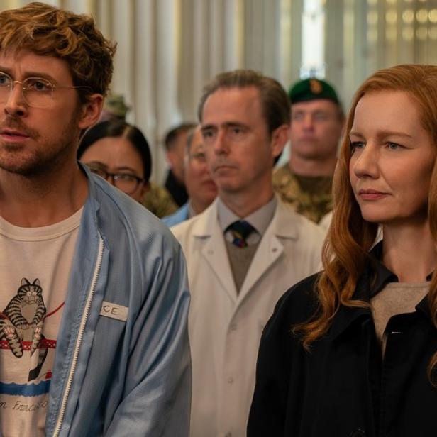 Ryan Gosling und Sandra Hüller stehen in Menschengruppe nebeneinander