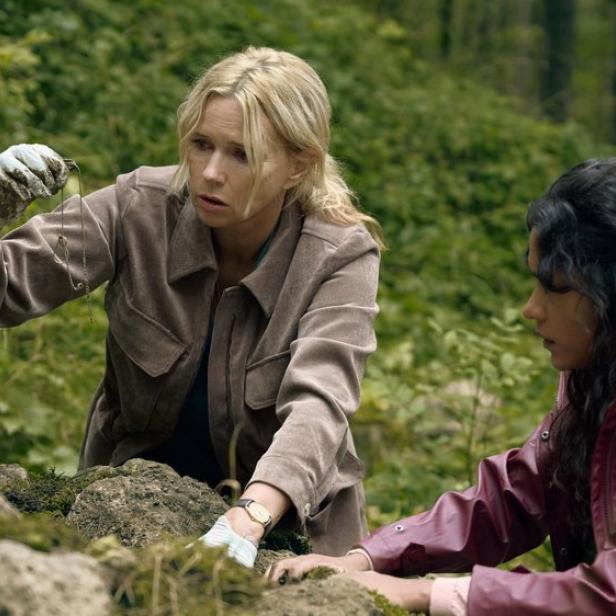 Zwei Frauen suchen nach Spuren unter Steinen im Wald