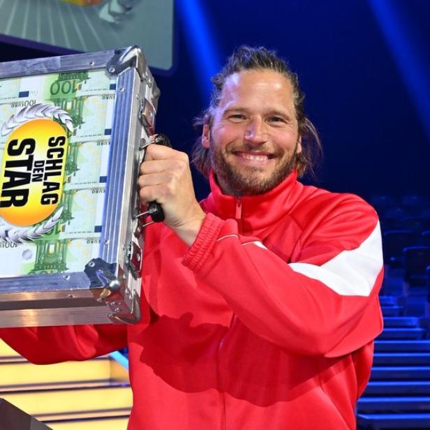 Sebastian Ströbel hält den Geldkoffer lächeln hoch