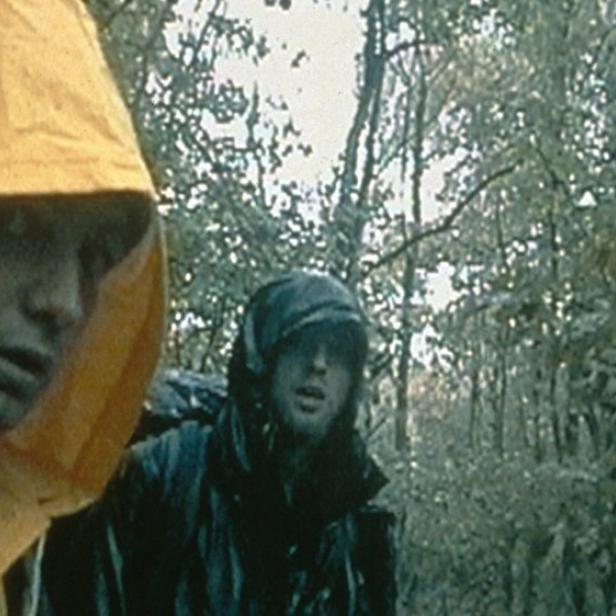 Zwei Männer mit Regenumhängen in einem nassen Wald