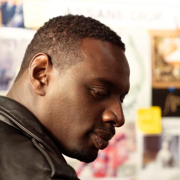Omar Sy blickt als Lupin nachdenklich vor einer Pinnwand mit verschiedenen Dokumenten und Notizen.