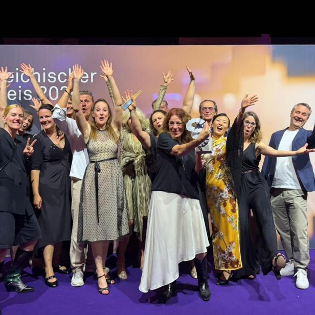 Gruppe von Menschen feiert auf einer Bühne vor der Aufschrift „Österreichischer Filmpreis 2026“.