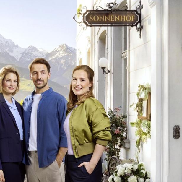 Drei Personen stehen vor dem Haus „Sonnenhof“ vor Alpenpanorama.