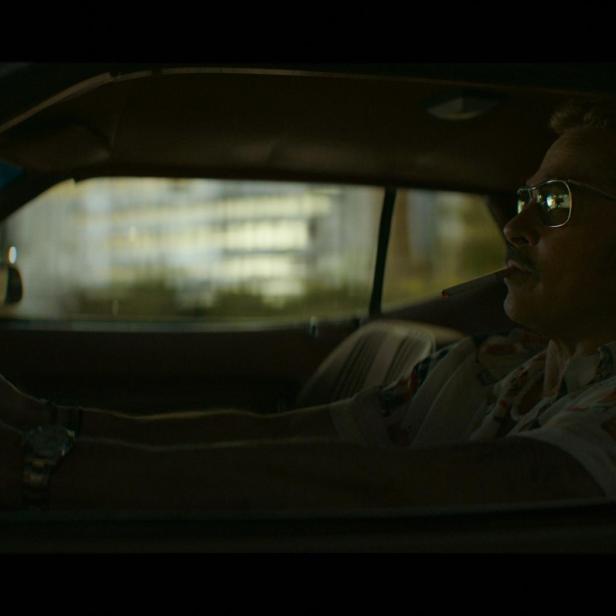 Brad Pitt fährt bei Nacht in einem Auto und raucht eine Zigarette.