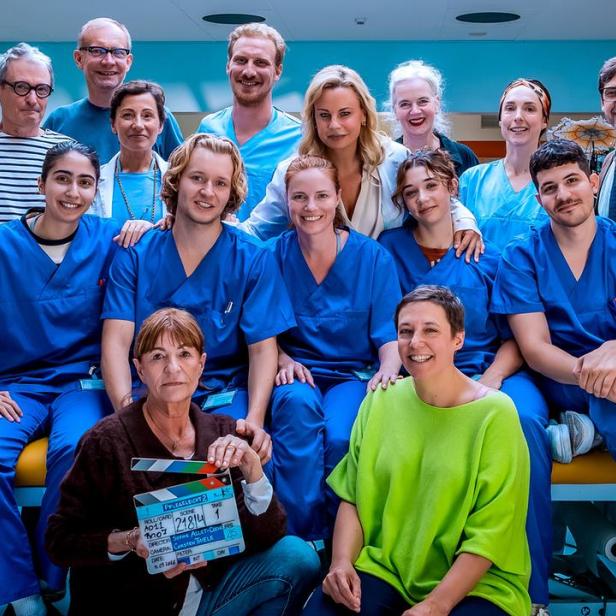 Die Besetzung und Crew der Serie „Pflegeleicht“ posieren gemeinsam in einem Krankenhausset.